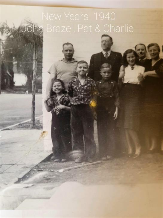 Group of seven family members posed together outdoors, smiling, in a vintage setting.