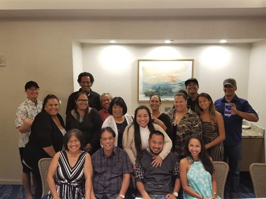 A lively family gathering features a diverse group of people smiling and posing together.