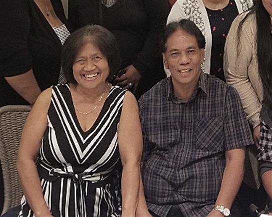 A joyful couple poses together in cheerful attire during a family gathering with friends.