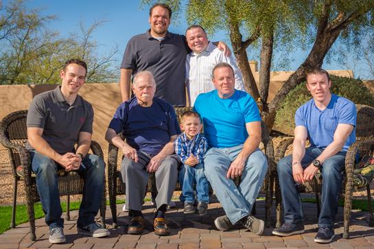 A cheerful family gathers outdoors, sharing smiles and embracing togetherness in sunlight.