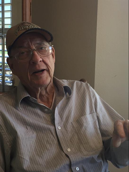 An elderly man shares captivating stories at a community center, engaging his listeners.