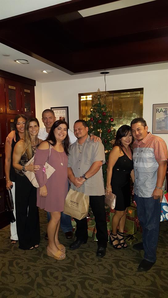 Group of friends happily posing together in a festive setting with a Christmas tree.