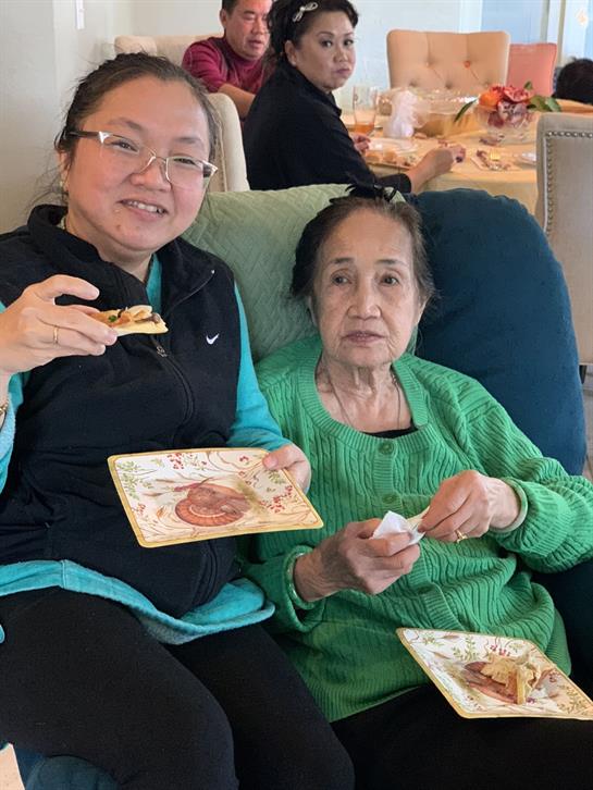 Two family members enjoy snacks together in a lively, comfortable setting.