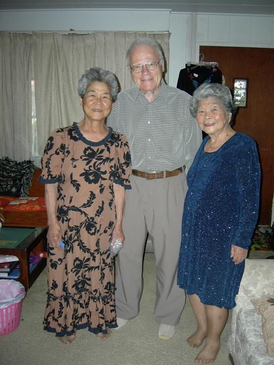 Three older adults smile together, enjoying their company in a cozy living space.