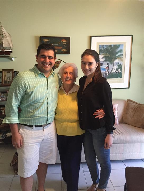 Three family members pose happily together in a warm living room filled with memories.