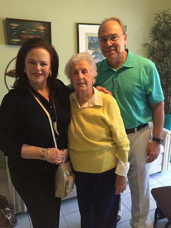 Three people smile in a cozy living room during a joyful family gathering.