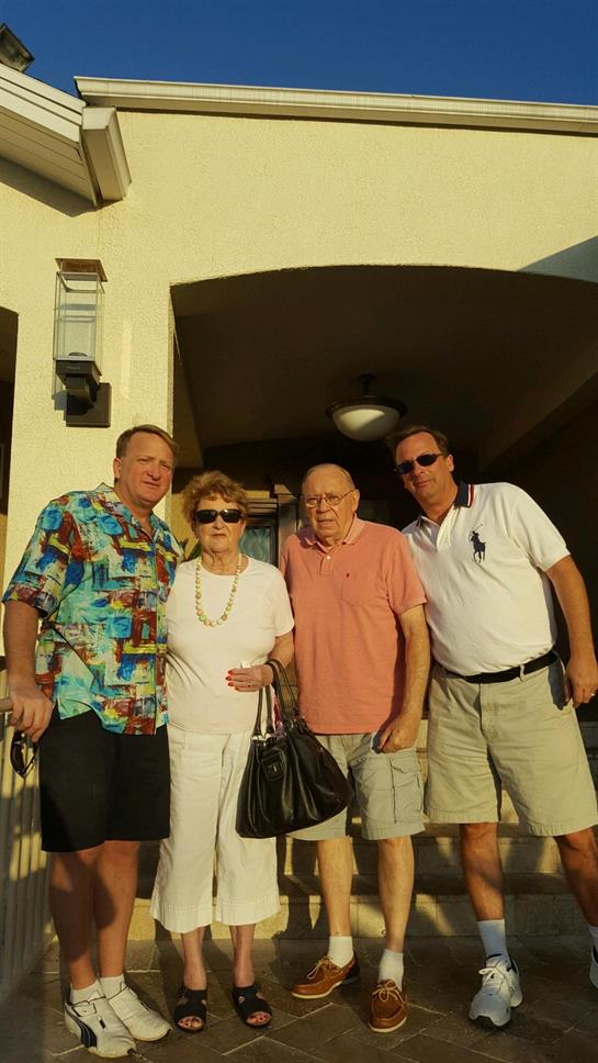 Four friends pose together outside a building basking in warm sunlight as they share smiles.