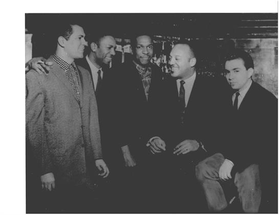 Influential figures engage in conversation and camaraderie at a social event in the 1960s.