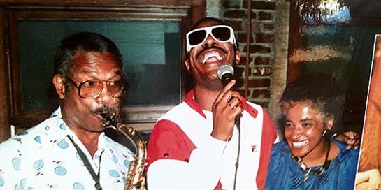 Talented saxophonist and vocalist entertain a cheerful audience in a busy venue.