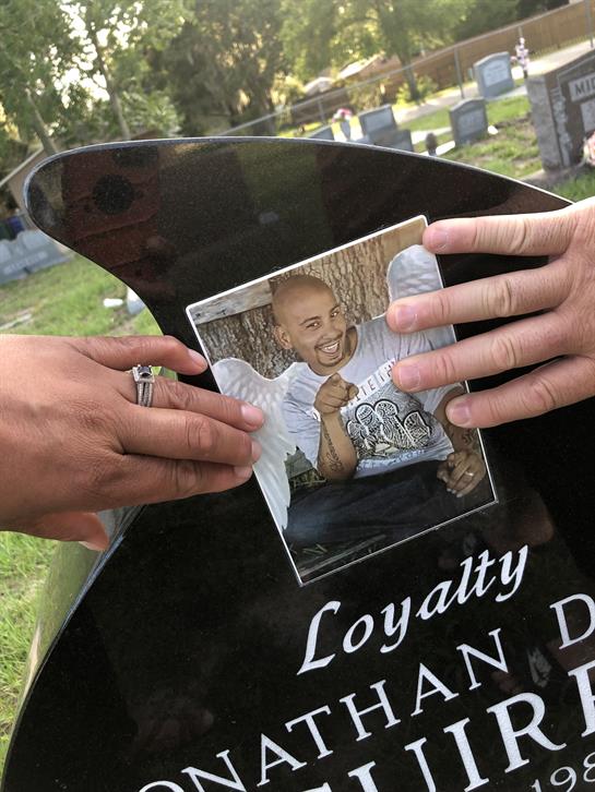 Family members place a cherished photo on a gravestone while remembering their loved one.