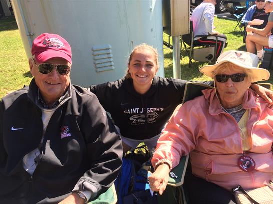 Three family members pose for a cheerful moment outdoors on a sunny day in the park.