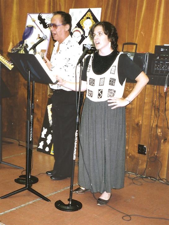 Two performers engage the audience with traditional songs at a cultural event.