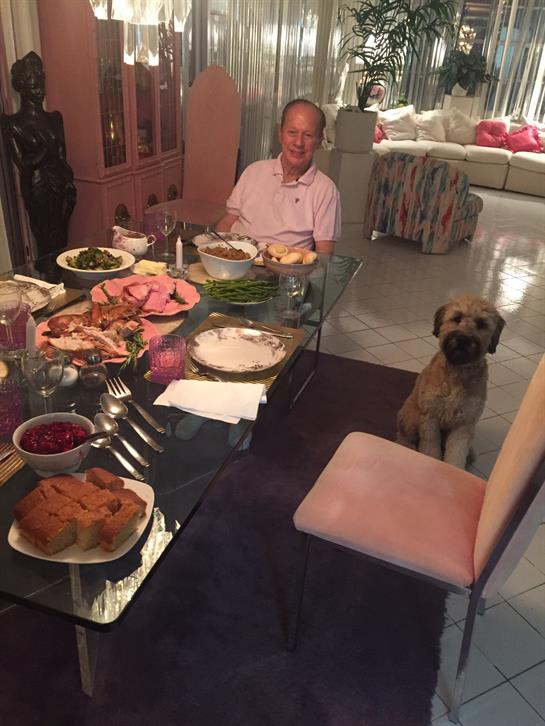 A joyful family dinner features various dishes while a dog sits attentively by the table.
