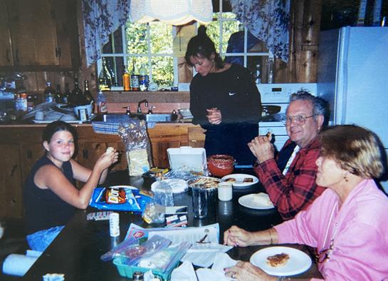 Four family members share food and laughter at the kitchen table, enjoying time together.