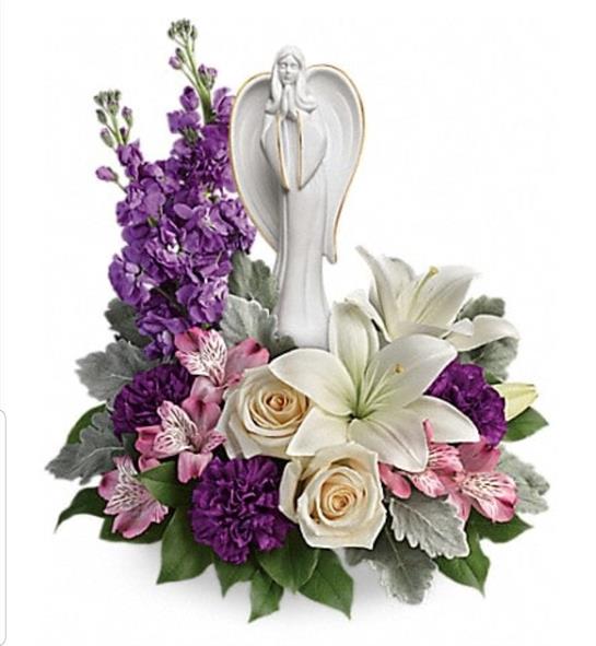 A lovely floral display features an angel figurine with purple and white flowers for serenity.