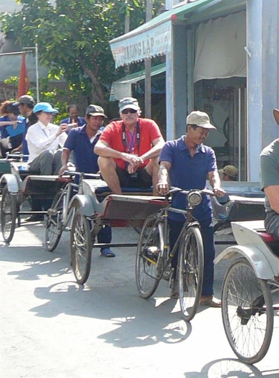 Pedicabs fill a busy street where passengers unwind and drivers enjoy the vibrant market.