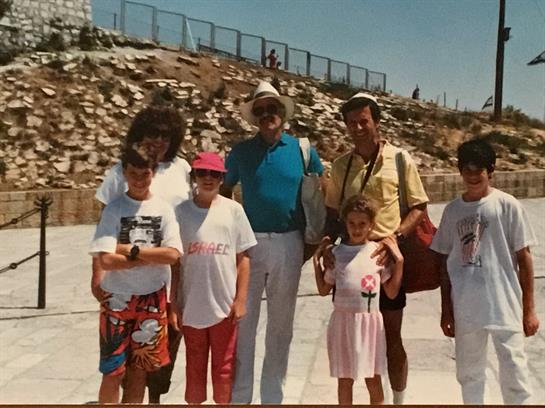 Group of children and adults pose together while enjoying a summer day near ancient ruins.