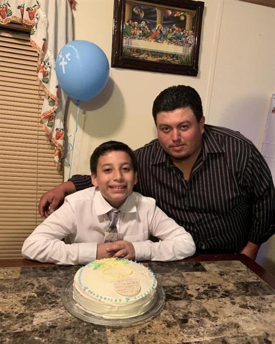 Father and son enjoy a joyful moment together at a birthday celebration in a warm, decorated room.