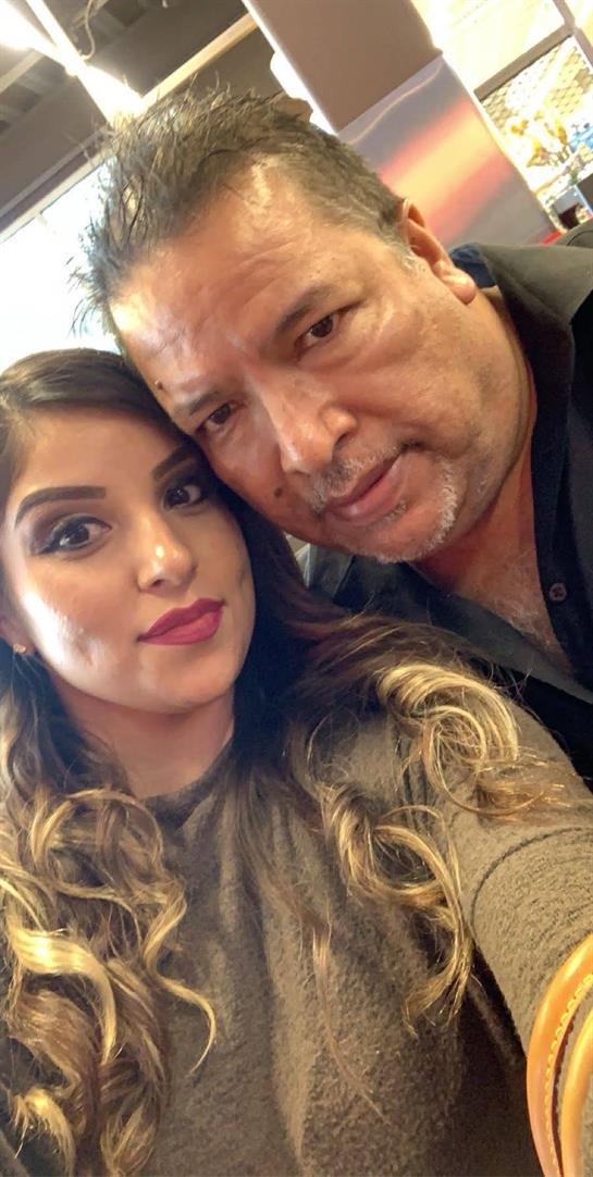 A young woman and an older man smile warmly for a selfie, showcasing their close relationship.