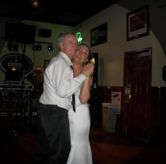 A couple shares a romantic dance in a festive atmosphere filled with music and laughter.