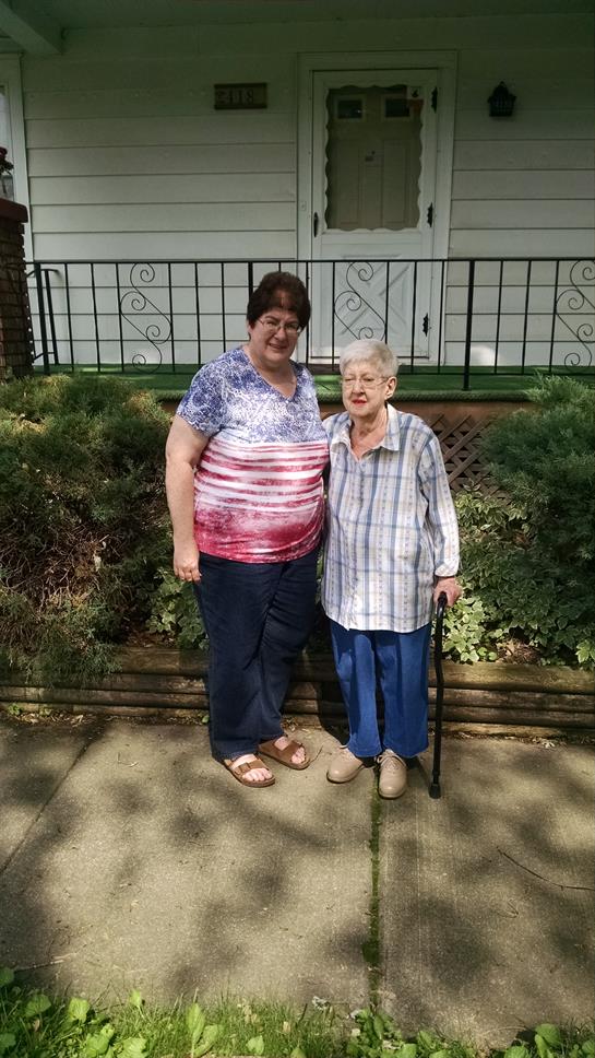 Two women share a moment outside a house, enjoying each other's company and the nice weather.