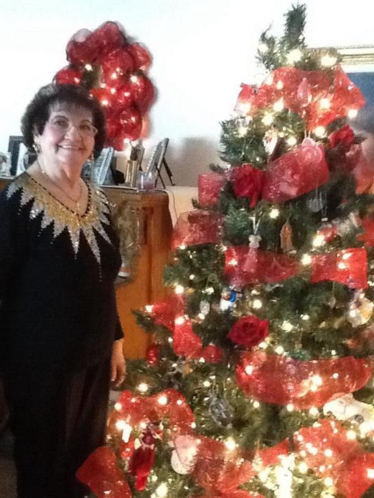 A joyful woman in a festive outfit enjoys the holiday spirit next to a decorated Christmas tree.