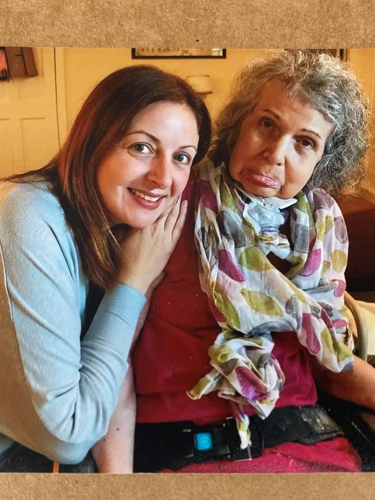 Two women share a joyful moment in a cozy living room, showcasing their close relationship.