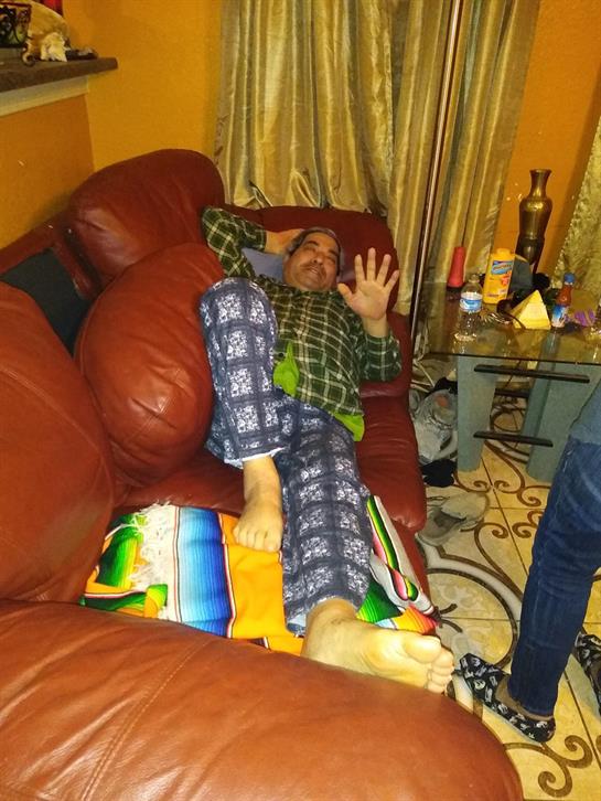 A person in pajamas playfully poses on a red couch in a cozy living room.