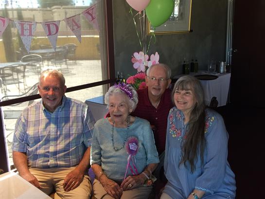 Family members celebrate a birthday with warm smiles and colorful decorations at a restaurant.