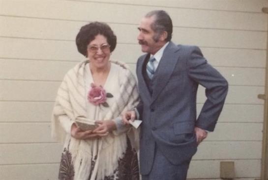 A man and woman are dressed formally, enjoying a cheerful moment at a gathering.