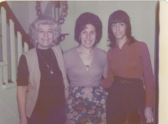 Women smile and stand close together, dressed in stylish clothes typical of the 1970s era.