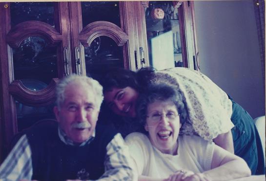 Three family members share a joyful moment, smiling and enjoying each other's company indoors.