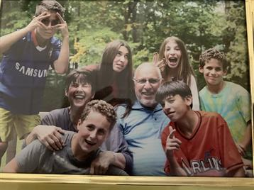 A joyful gathering of kids and an adult enjoying their time outdoors, smiling and posing together.