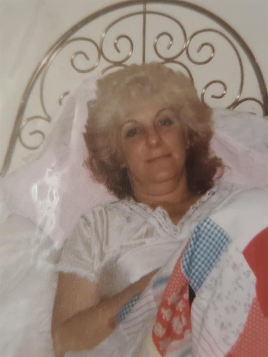 A woman with blonde hair is resting comfortably in bed, surrounded by a colorful quilt.