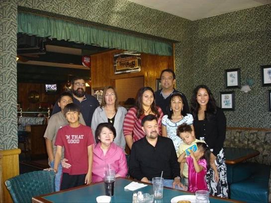 A large family enjoys a festive gathering at a cozy restaurant during evening hours.