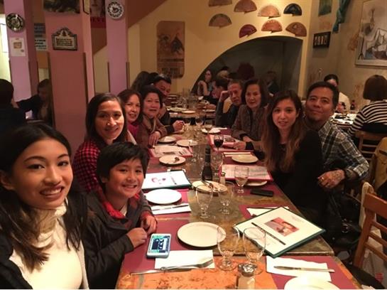 A group of friends enjoys a lively dinner at a bustling restaurant, sharing laughs and food.