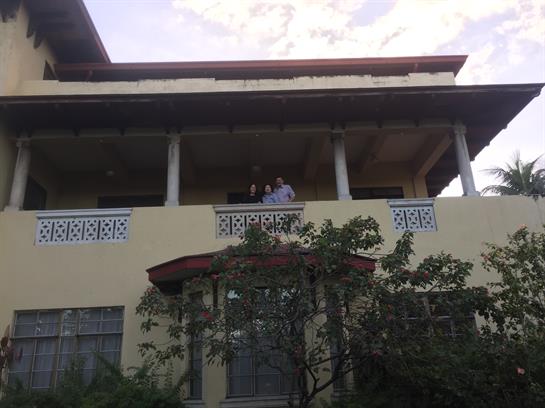 Two people stand on a balcony enjoying the warm afternoon light in a historic structure.