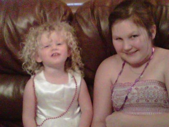 Two girls share smiles while sitting on a leather couch, enjoying each other's company at home.