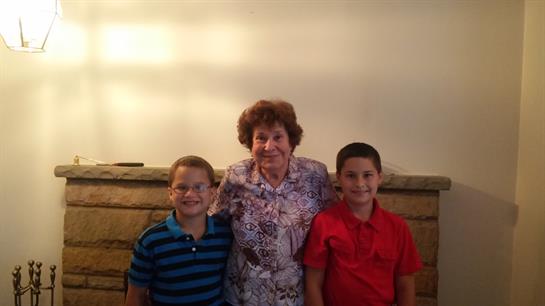 Grandmother poses with two children in a warm, inviting indoor environment.