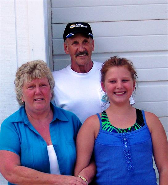 A cheerful family poses together outside in bright summer outfits, smiling happily.