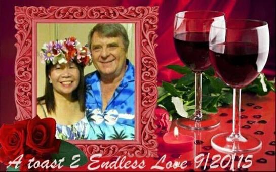 Happy couple poses together, surrounded by flowers and wine glasses, celebrating a special moment.