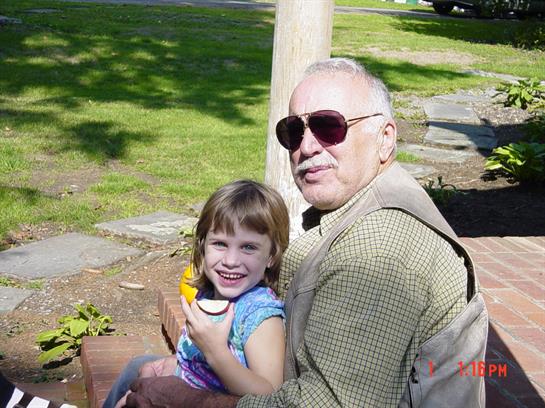 Grandfather and young girl share a joyful moment eating ice cream while sitting outside.