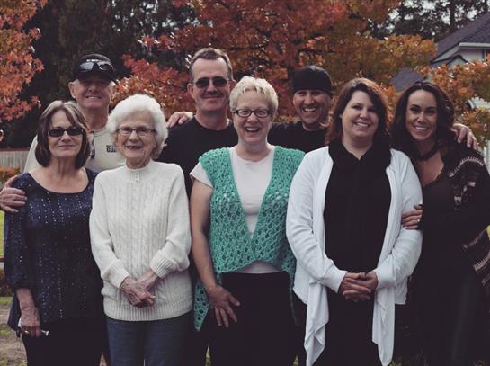 A joyful family poses together outdoors surrounded by vibrant autumn foliage.