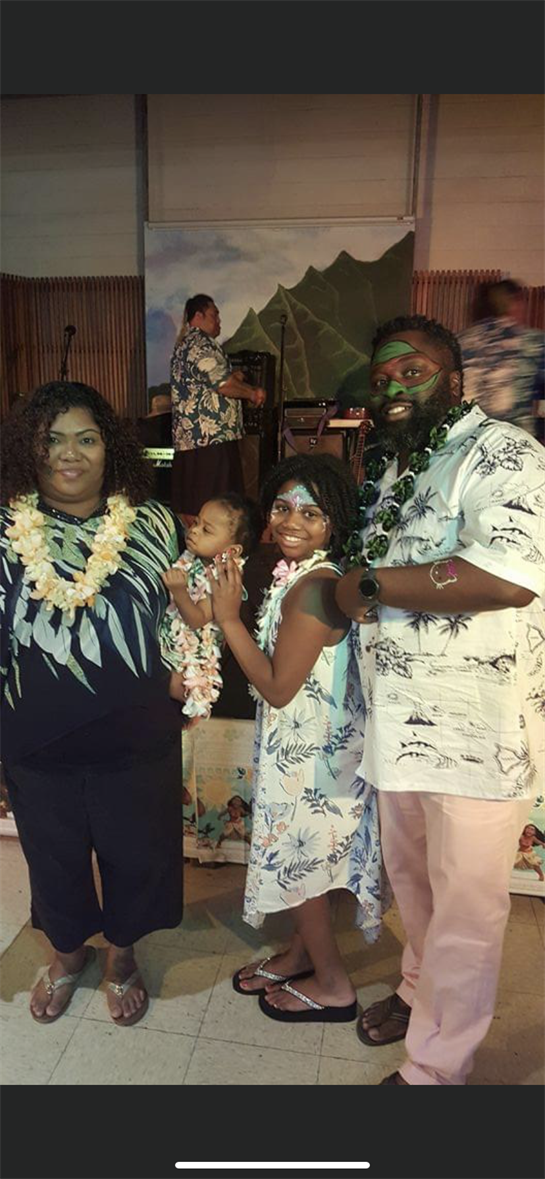 Family members dressed in colorful outfits and floral leis celebrate together during a joyful event.