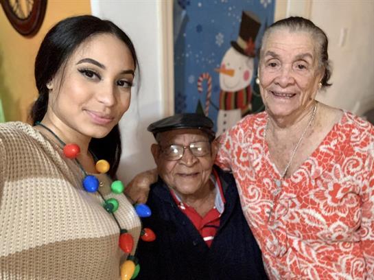 Three family members smile together, celebrating joy and warmth at a holiday gathering.