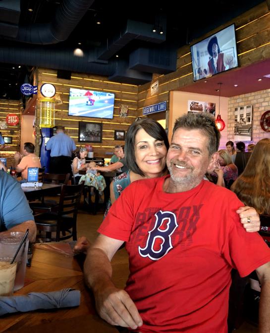 A man and woman share a joyful moment at a busy restaurant filled with friends and good food.