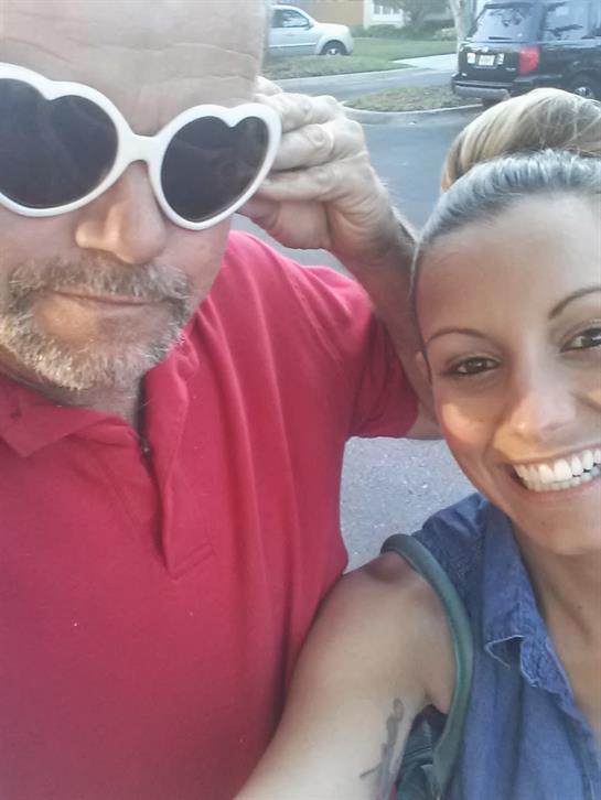 A cheerful couple poses together outdoors, wearing heart-shaped sunglasses and smiling happily.