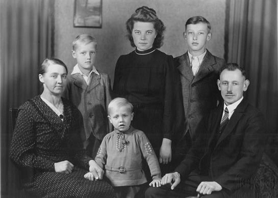 A family poses in a vintage portrait, united in timeless outfits.