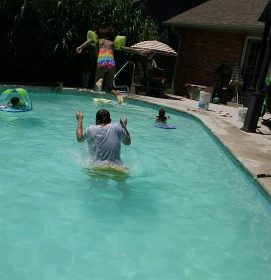 Group of friends enjoying a lively summer day swimming, splashing, and playing at a backyard pool.