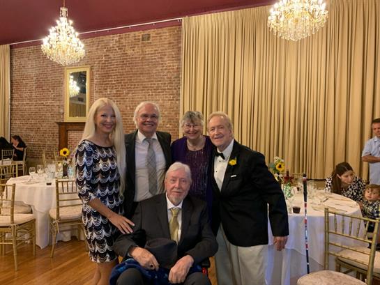 Five friends gather joyfully in a stylish venue, reminiscing and enjoying one another.